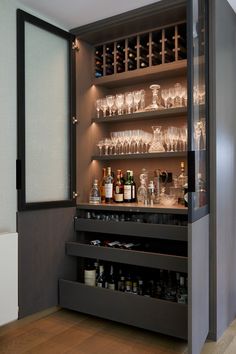 an open cabinet filled with lots of bottles and glasses