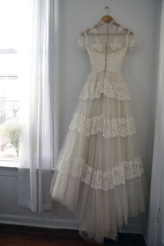 a white dress hanging on a wall next to a window