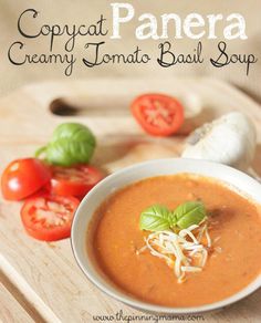 a bowl of creamy tomato basil soup on a cutting board