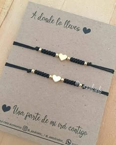 two black cord bracelets with gold heart charms on each one, sitting on top of a card