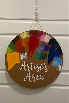 a sign that says artist's area hanging from the wall with paintbrushes painted on it