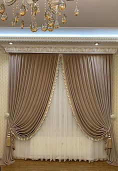 a room with curtains, chandelier and lights on the ceiling is decorated in gold