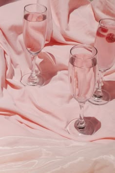 three wine glasses sitting on top of a pink blanket