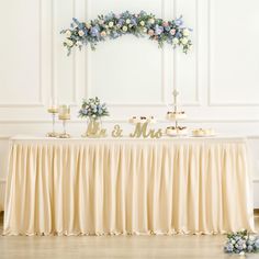 the table is set up for a wedding reception with flowers and candles on it, along with an mr and mrs sign