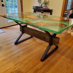 a glass table sitting on top of a wooden floor next to a dog in a living room