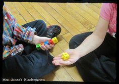 two children sitting on the floor playing with blocks in their hands and one child holding out his hand