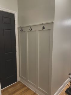 an empty room with two coat hooks on the wall and a black door in the background