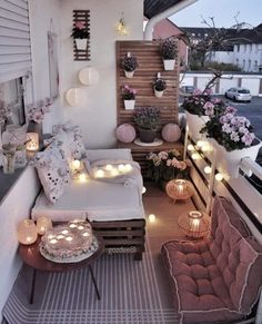 the balcony is decorated with candles, flowers and potted plants on wooden pallets