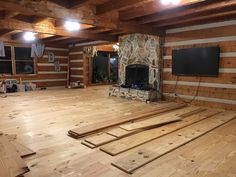 an unfinished room with wood flooring and stone fireplace