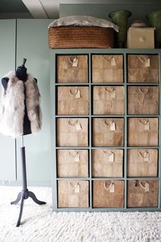 a fur vest is hanging on a coat rack in front of a white carpeted floor