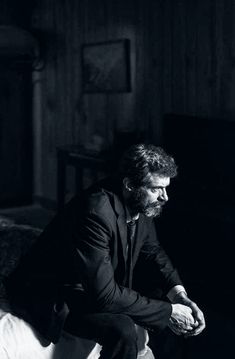 a man sitting on top of a bed next to a black and white piano in a dark room