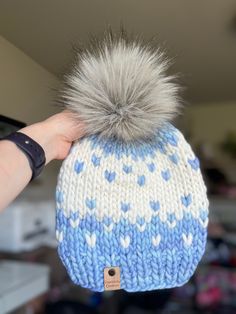 a blue and white knitted hat with grey pom - pom on top