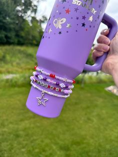 a person holding up a purple coffee cup with bracelets on it and the words happy birthday