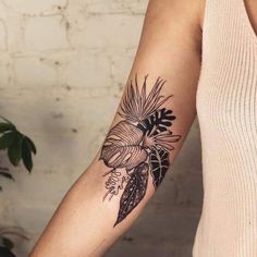 a woman with a black and white tattoo on her arm, holding a potted plant