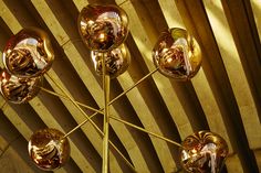 a gold colored chandelier hanging from the ceiling in a room with wooden walls