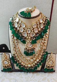 a green and white jewelry set with matching necklaces, earrings and ring on display