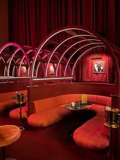 a restaurant with red walls and booths in the center, along with orange couches