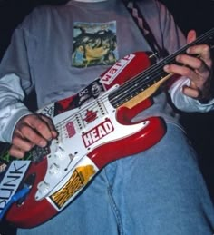 a person holding a red and white guitar