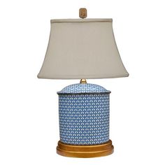 a blue and white lamp on a wooden base with a light shade over the top