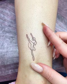 a person with a small tattoo on their arm holding onto her leg and pointing to the side