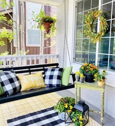 a porch swing with pillows and flowers on it