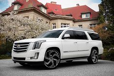 a white suv parked in front of a large house