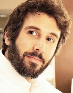 a close up of a person wearing a white shirt and tie with a goatee