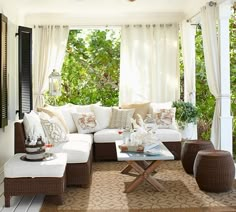 a living room filled with lots of furniture under a covered patio area next to trees