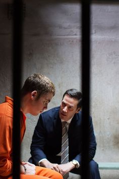 two men in suits sitting on the ground