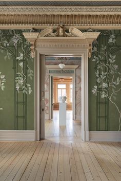 an empty room with green wallpaper and white columns in the center, along with wooden flooring