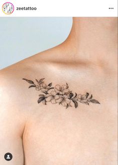 a woman's chest with flowers and leaves tattooed on the back of her shoulder