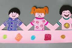 three paper dolls holding hands over a pink surface