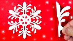 someone is cutting out a paper snowflake on a red background with white stars