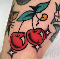 a close up of a person's arm with tattoos on it and two cherries