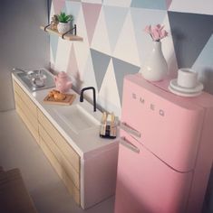 a pink refrigerator freezer sitting next to a white sink in a room with geometric wallpaper