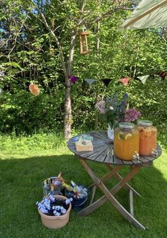 a picnic table with mason jars and flowers in the back yard, under an umbrella