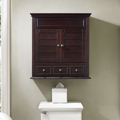 a white toilet sitting next to a wooden cabinet on top of a bathroom wall above it