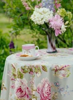 a table topped with a plate of food next to a vase filled with pink flowers