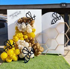 some balloons are sitting on the grass near a building and beehive shaped wall