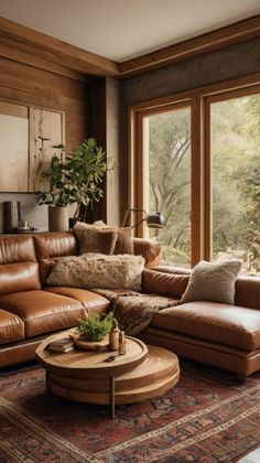 a living room with leather furniture and large windows looking out onto the trees outside,