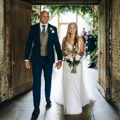 the bride and groom are walking down the hall together in their wedding attire, holding hands