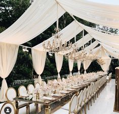 a long table with white chairs and chandeliers