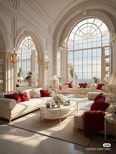 an elegant living room with large arched windows and white couches, red pillows, and chandelier