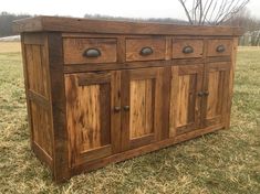 a wooden cabinet sitting on top of a grass covered field