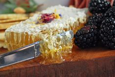 a piece of cake sitting on top of a wooden cutting board next to blackberries