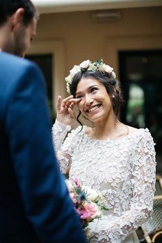 a woman in a white dress smiles as she holds her hand up to her face