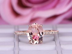 an engagement ring with a pink diamond in the center and rose petals in the background