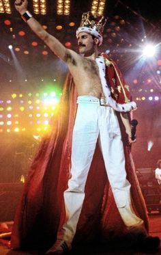 a man in white and red costume standing on stage with his arms up to the side