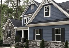 a blue house with white trim and black shutters on the front, and two story windows