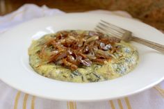 a white plate topped with an omelet covered in toppings and a fork